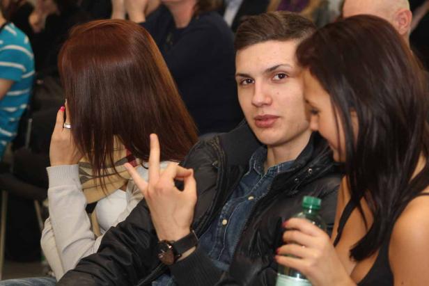 Ein junger Mann sitzt zwischen zwei Frauen.