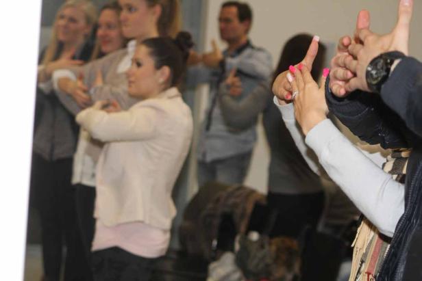 Eine Gruppe von Menschen macht eine Übung mit ihren Händen.