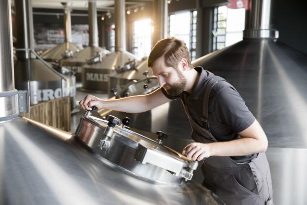 Ein Brauer öffnet einen Tank in einer Brauerei.