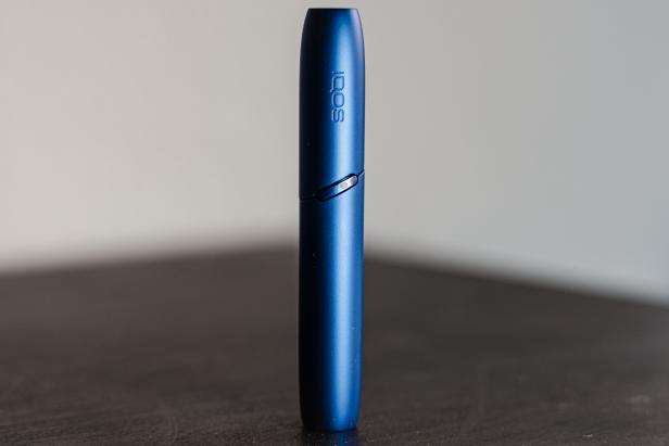 Ein blaues IQOS-Gerät steht auf einer dunklen Oberfläche.