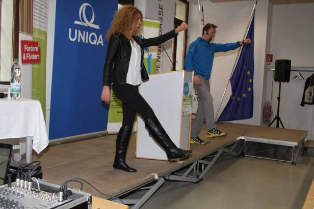 Eine Frau und ein Mann stehen auf einer Bühne und gestikulieren.