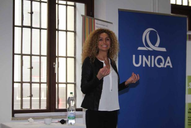Eine Frau präsentiert vor einem Banner der UNIQA Versicherung.