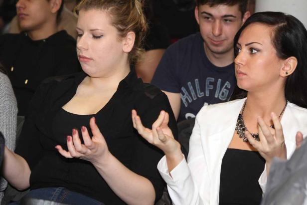 Zwei Frauen gestikulieren während einer Veranstaltung.