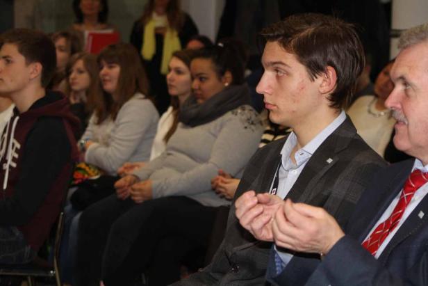 Zuschauer sitzen während einer Veranstaltung in einer Reihe.