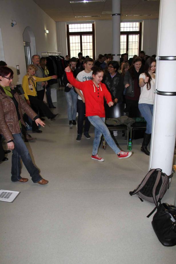 Eine Gruppe von Menschen tanzt in einem hellen Raum.