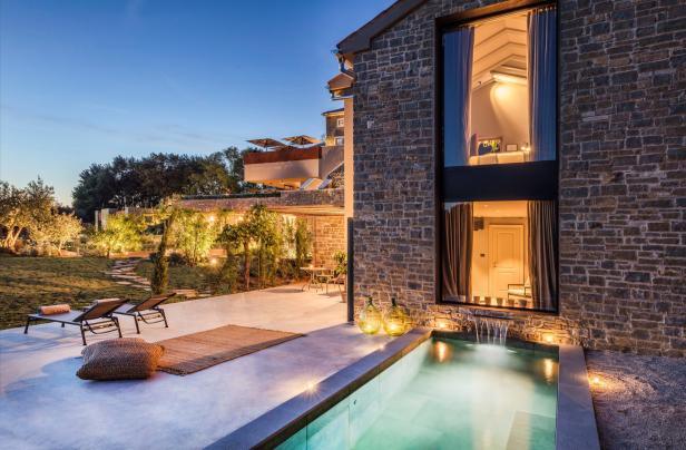 Ein luxuriöses Steinhaus mit Pool und Garten in der Abenddämmerung.