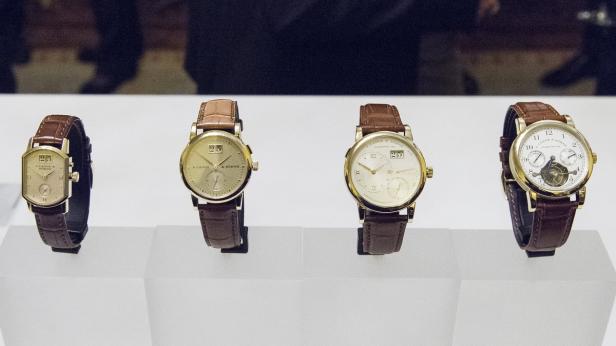 Vier goldene A. Lange & Söhne Uhren mit braunen Lederarmbändern stehen auf einem Display.