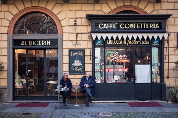 Ein Paar sitzt vor den Cafés „Al Bicerin“ und „Caffè Confetteria“.