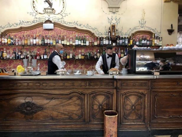 Zwei Barkeeper arbeiten hinter einer Bar mit vielen Spirituosenflaschen.