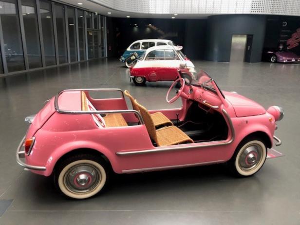 Ein rosafarbenes, offenes Fiat 500 Jolly Modell steht in einer Ausstellung.
