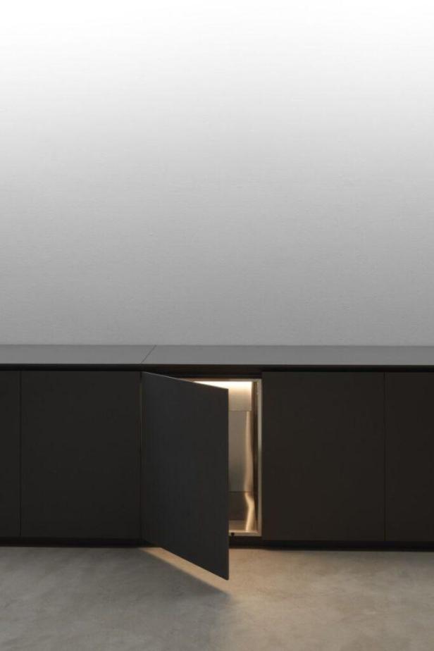 Ein dunkler Küchenschrank mit einer leicht geöffneten Tür, aus der Licht scheint.