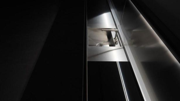 Ein moderner, minimalistischer Küchenschrank mit Edelstahloberfläche.