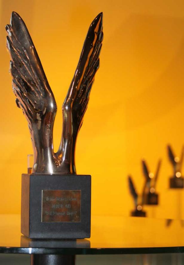 Eine bronzene Flügel-Skulptur steht auf einem schwarzen Sockel.