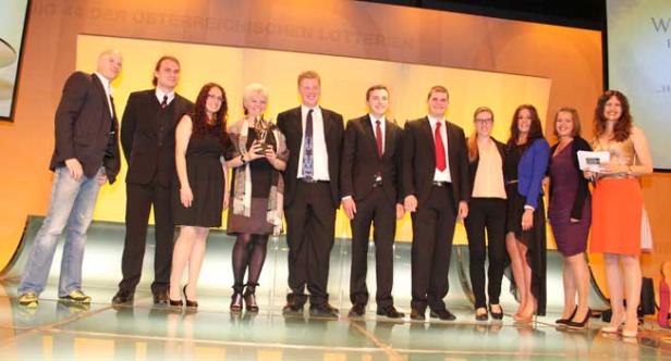 Eine Gruppe von Menschen posiert auf einer Bühne für ein Foto.