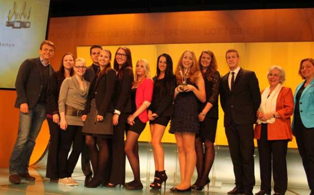 Eine Gruppe von Menschen posiert auf einer Bühne mit einer goldenen Trophäe.