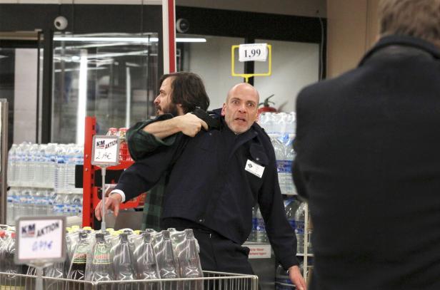 Ein Mann bedroht einen Supermarktangestellten mit einer Waffe.