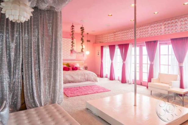 Ein pinkfarbenes Schlafzimmer mit silbernen Vorhängen und einer Stange in der Mitte des Raumes.