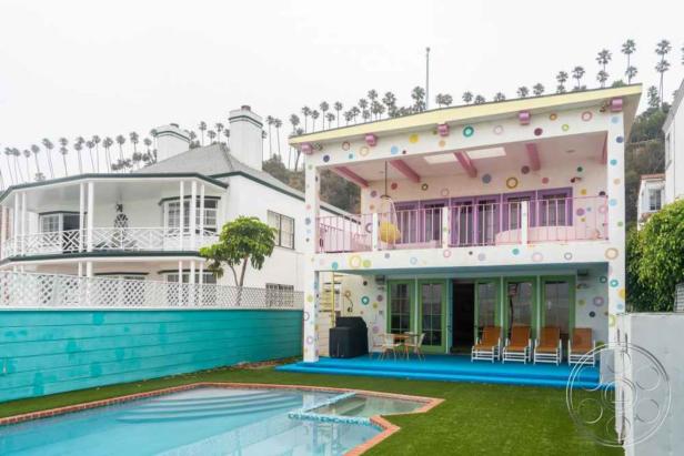 Ein buntes Haus mit Pool und einem traditionellen Haus im Hintergrund.