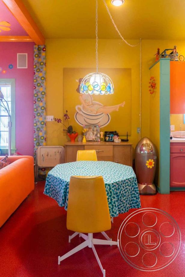 Ein farbenfrohes Esszimmer mit gelben Stühlen und einem runden Tisch mit blau gemusterter Tischdecke.