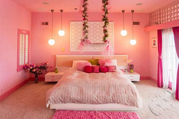 Ein rosa Schlafzimmer mit einem Bett, das mit Herzförmigen Kissen dekoriert ist.