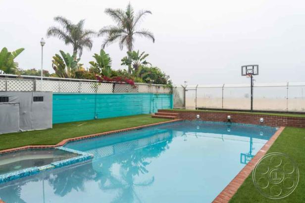 Ein Swimmingpool mit Basketballkorb und Palmen im Hintergrund.