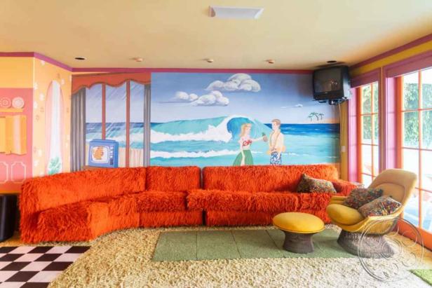 Ein Wohnzimmer mit einer Wandmalerei einer Strandszene und einem orangefarbenen Zottelsofa.