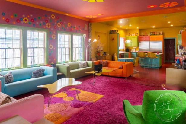 Ein farbenfrohes Wohnzimmer mit Sofas, Teppich und Blumenmustern an den Wänden.