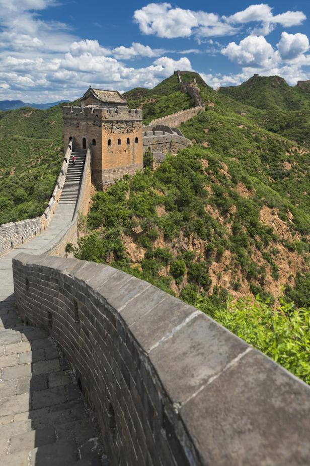 Ein Abschnitt der Chinesischen Mauer schlängelt sich über einen bewaldeten Hügel.