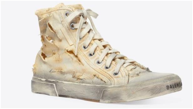 Ein abgenutzter, hochgeschnittener Balenciaga-Sneaker in Weiß vor einem weißen Hintergrund.