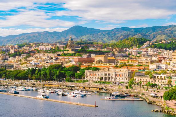 Blick auf Messina in Sizilien mit dem Hafen und der Stadt vor einer Bergkulisse.