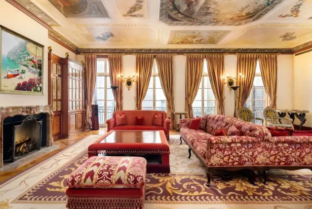 Ein opulent eingerichtetes Wohnzimmer mit Gemälden an der Decke und einem Kamin.