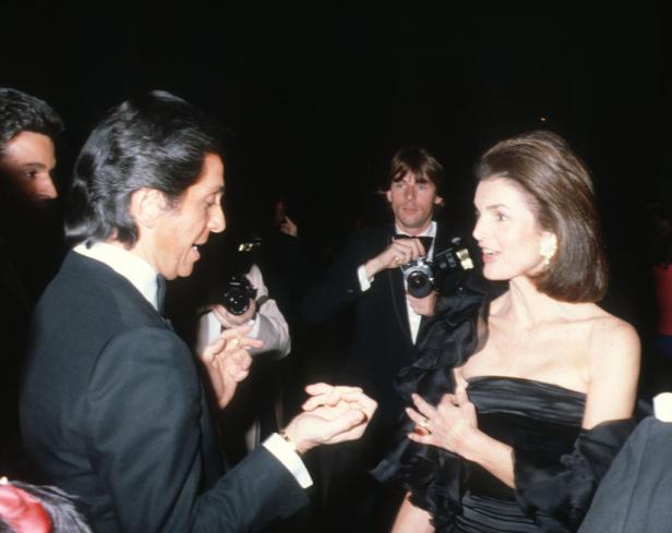 Jackie Kennedy spricht mit einem Mann, während Fotografen Fotos machen.