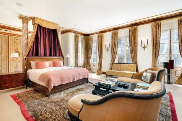 Ein Schlafzimmer mit Himmelbett, gemustertem Teppich und goldenen Akzenten.