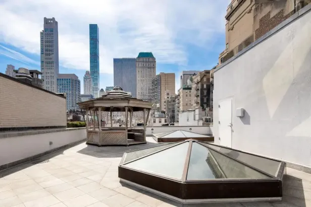 Ein Pavillon und pyramidenförmige Oberlichter auf einer Dachterrasse mit Blick auf die Skyline der Stadt.
