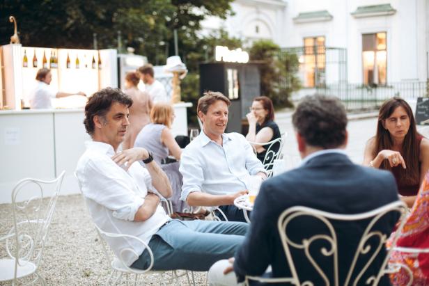 Menschen sitzen und unterhalten sich bei einer Gartenparty.
