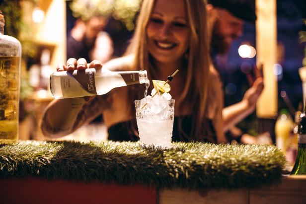 Eine Frau gießt Ingwerlimonade in ein mit Eiswürfeln gefülltes Glas.