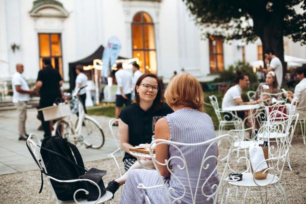 Zwei Frauen sitzen an einem Tisch im Freien und unterhalten sich.