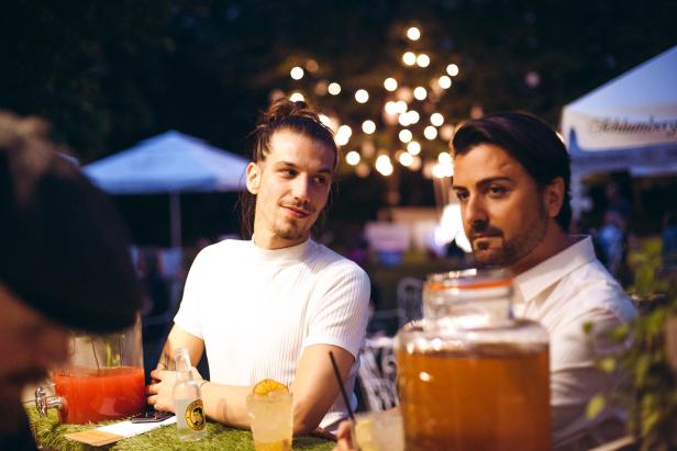 Zwei Männer sitzen an einem Tisch mit Getränken im Freien.