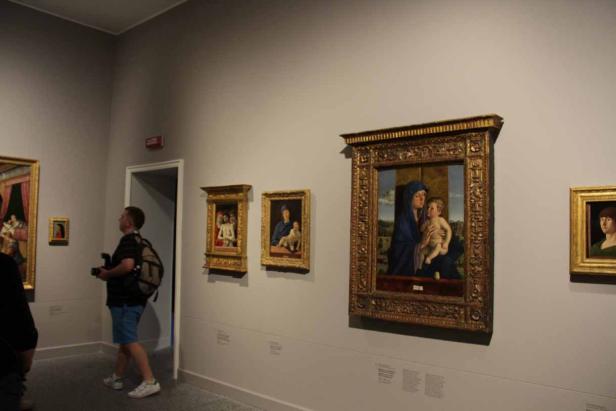 Ein Mann betrachtet Gemälde von Madonnen mit Kind in einem Museum.