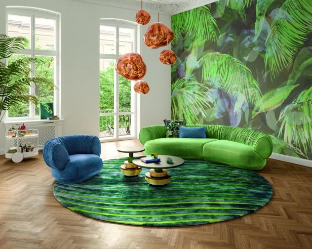 Ein Wohnzimmer mit grünen und blauen Möbeln und einer Dschungeltapete.
