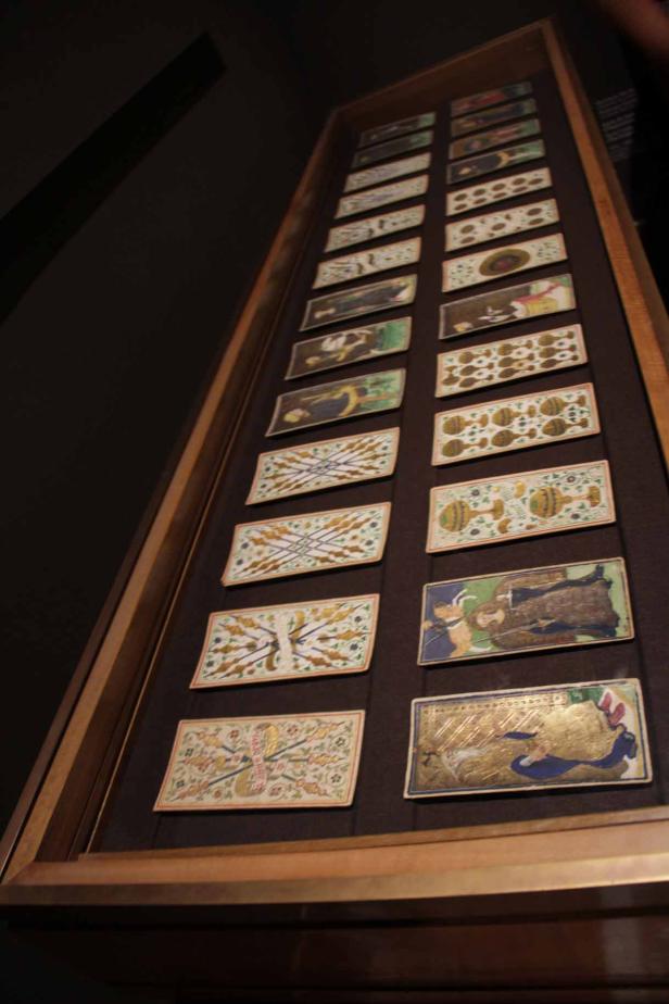 Eine Vitrine zeigt eine Sammlung von antiken Spielkarten mit verschiedenen Motiven.