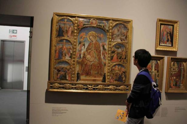 Ein Besucher betrachtet ein großes, golden gerahmtes Gemälde der Madonna mit Kind in einem Museum.