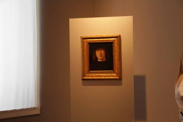 Ein Porträt eines Mannes mit Hut in einem goldenen Rahmen an einer Wand.