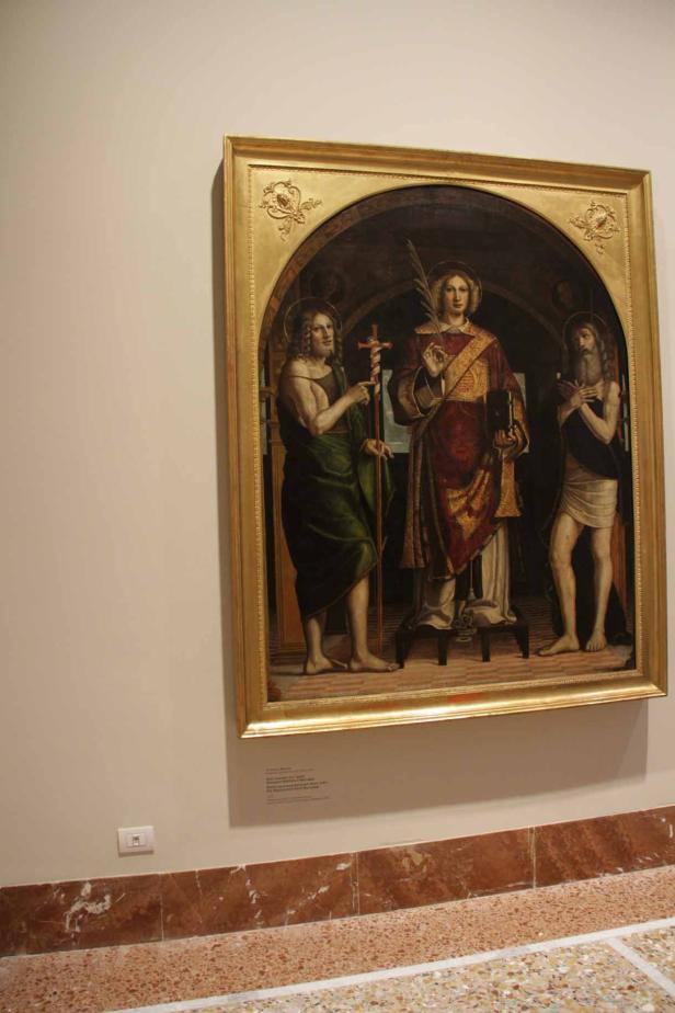 Ein Gemälde mit drei Heiligen in einem goldenen Rahmen.