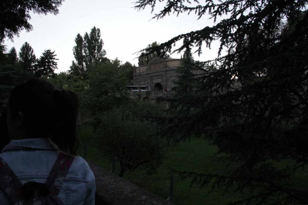 Eine Person blickt auf ein steinernes Gebäude in einem Park.