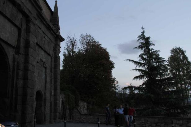 Eine Gruppe von Menschen steht vor einem alten Steingebäude im Freien.
