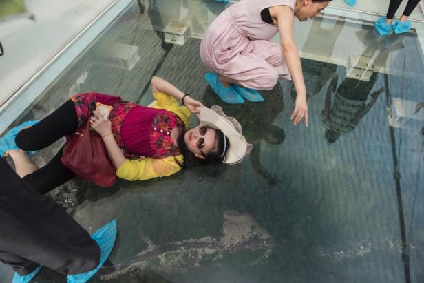 Zwei Frauen posieren auf einem Glasboden mit Blick in die Tiefe.