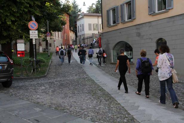 Eine Gruppe von Menschen geht eine Kopfsteinpflasterstraße entlang.