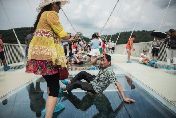 Besucher auf einer Glasbrücke in China, einige mit blauen Überschuhen.