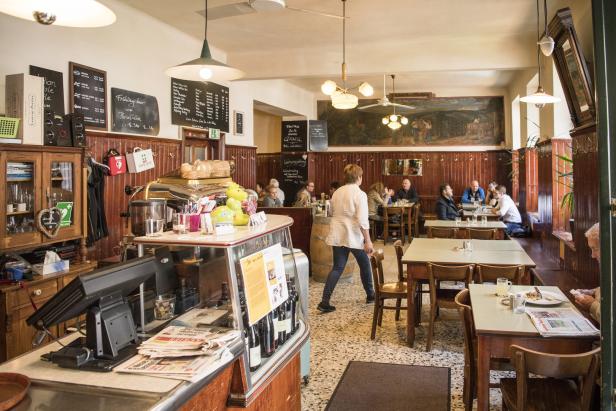 Innenansicht eines traditionellen Wiener Kaffeehauses mit Gästen an Tischen.